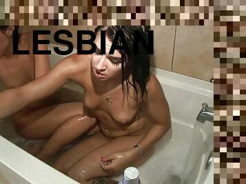 Two brunette lesbians fondle each other in a bathroom