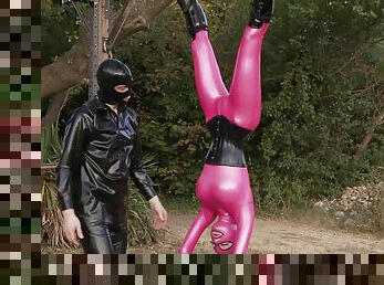 Babe in tight pink clothes is upside-down and sucking a latex cock