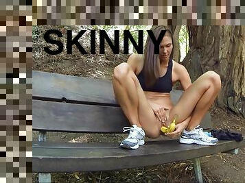 Skinny hussy Avia fucks her twat with a banana in a park