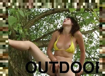 Teen in yellow bikini climbs up on a tree to masturbate on a branch