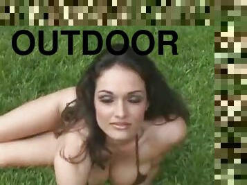 Stunning Kellie Maines lies on a lawn and shows her nude body