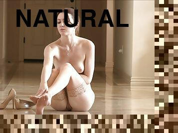 A slim girl with perky tits poses naked sitting on a floor
