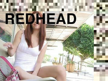 Redhead Melody fondles her tits and pussy sitting on a bench