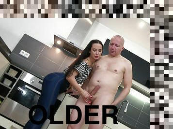 Older man gets his dick pleasured by a clothed teen in the kitchen