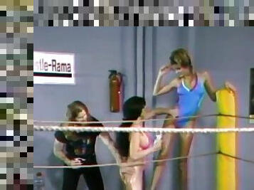 Two lesbians wearing swimsuits fight on a ring in retro clip