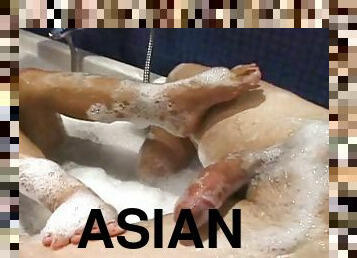 Brunette Asian bitch with natural tits stroking a man in the tub