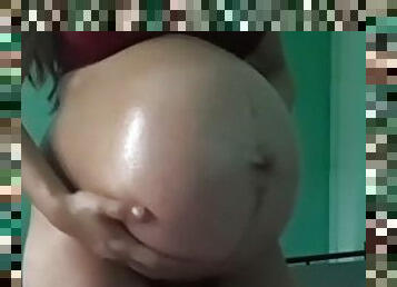 Asian girl oils her huge belly