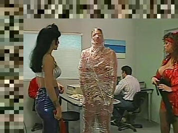 Mistresses cover a man in tight plastic wrap