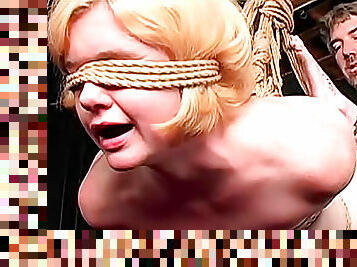 Blindfolded blonde girl in rope bondage suspension