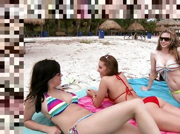 Three beautiful girls sunbathe and have fun on the beach