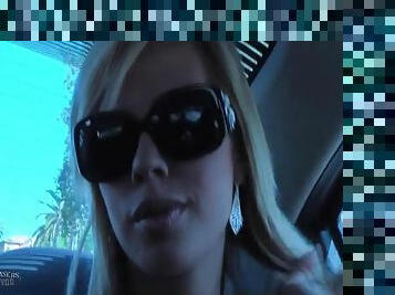 Pretty blonde in sunglasses chats in the car