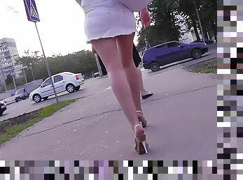 Hot babe in short white dress is walking on the street