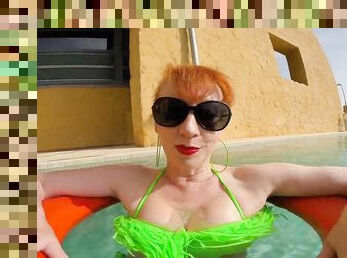 Beautiful busty redhead mature is out in the pool in her green bikini