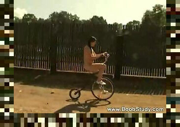 Girl in pigtails riding her bike naked